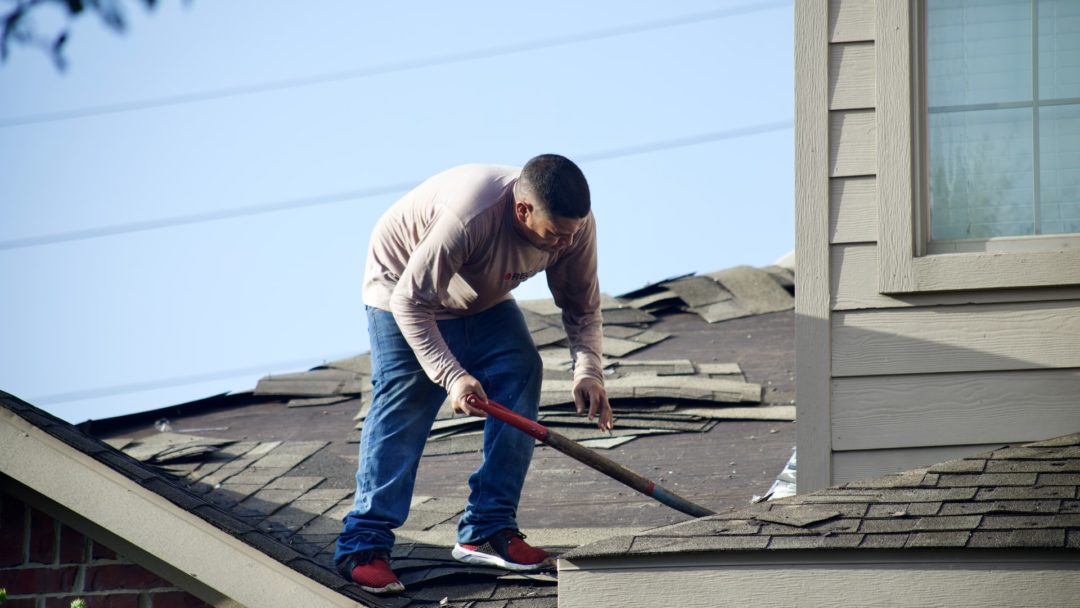 roofer checking out roof damage after a storm